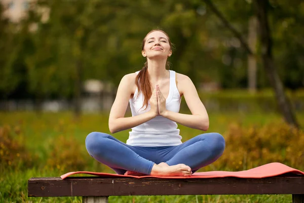 Mujer feliz hace entrenamiento de yoga en estera en jardín. — Foto de Stock