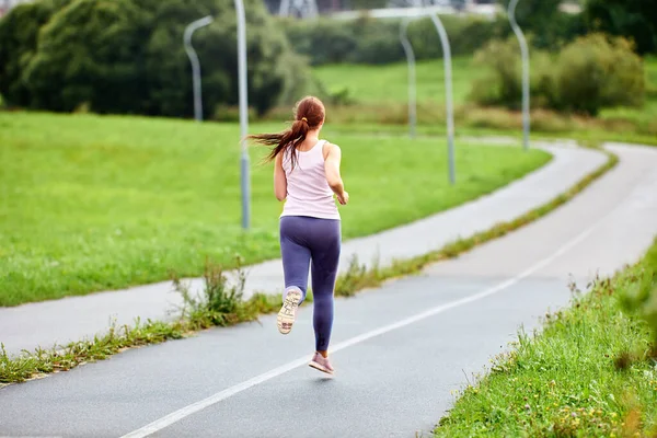 Visão traseira da mulher correndo na estrada na manhã de verão. — Fotografia de Stock