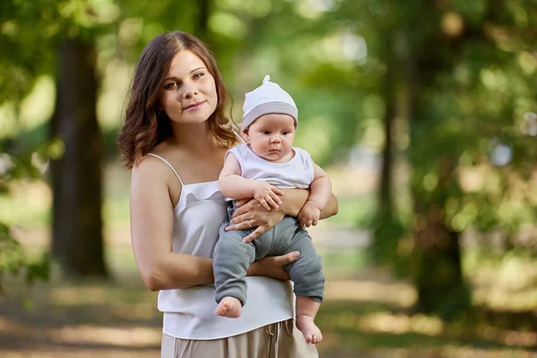 Young mother with nursing baby in her arms in public park. — Stock Photo, Image