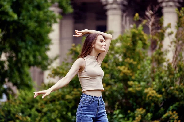 Mulher branca esbelta, 18 anos, em frente à colunata do edifício histórico na cidade europeia. — Fotografia de Stock