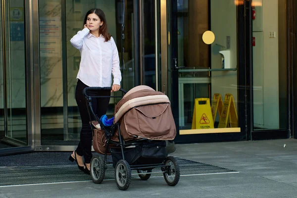 Kvinna med liten unge i barnvagn går utomhus. — Stockfoto