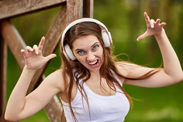 Mujer en auriculares inalámbricos hace mueca al aire libre. — Foto de Stock