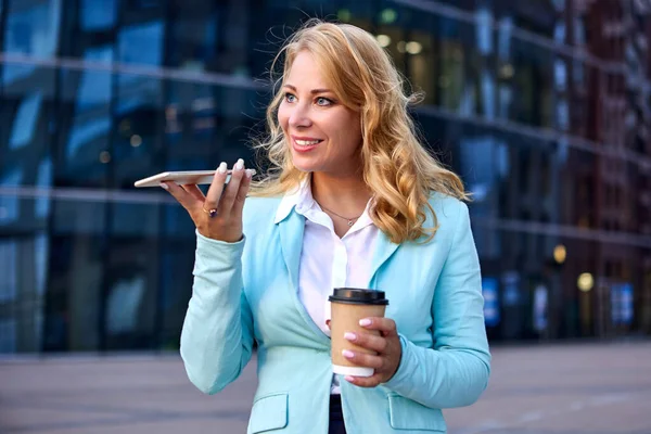 Bizneswoman trzyma papierową filiżankę kawy w rękach i rozmawia przez telefon. — Zdjęcie stockowe