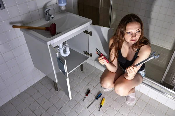 Sink siphon is clogged woman chooses tool to disassemble it. — Stock Photo, Image