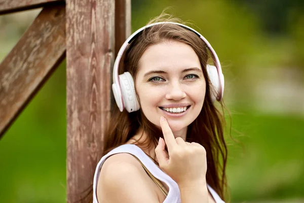 Szczęśliwa kobieta w słuchawkach bezprzewodowych jest chodzenie na zewnątrz. — Zdjęcie stockowe