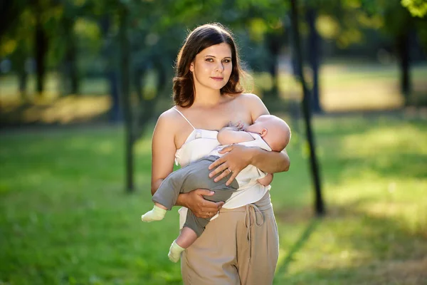 Openbare borstvoeding in park door vrouw met baby. Stockfoto