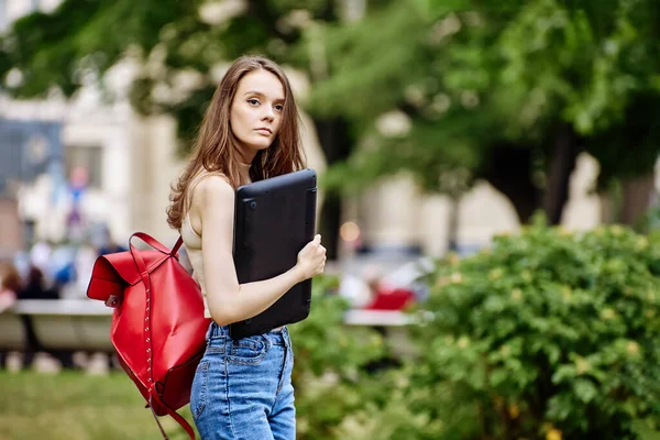 Sottile donna europea tiene il computer portatile nel parco. — Foto Stock