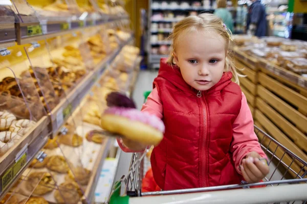 Kvinna spädbarn 3 år gammal håller munk i snabbköpet. — Stockfoto