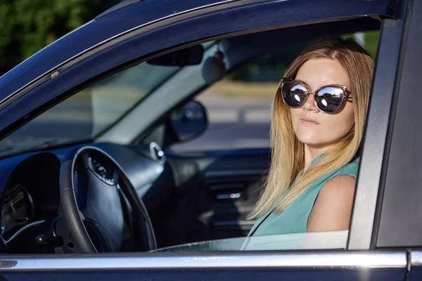 Blanke jonge vrouw met een zonnebril rijdt auto. — Stockfoto