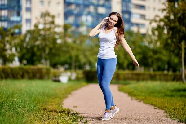 Sourire femme caucasienne parle par smartphone en plein air. — Photo