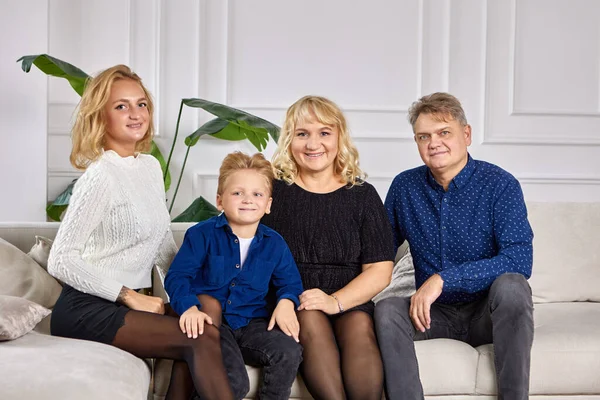 Happy family sits on sofa in living room. — Stock Photo, Image