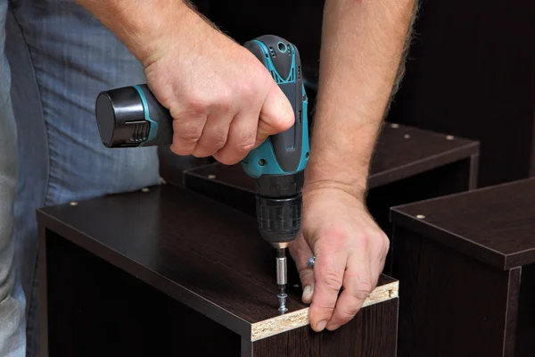 Hands carpenter with screwdriver, tighten screw in drawers of chipboard. — Stock Photo, Image