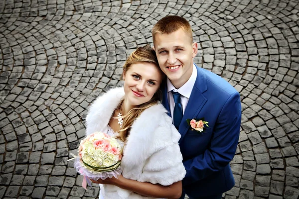 Newlyweds smiling, view from above, on a background of cobblestones. — Stock Photo, Image