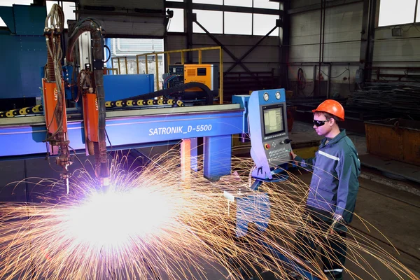 Arbeiter steht in der Nähe der Maschinensteuerung und schneidet Plasma-Metall. — Stockfoto