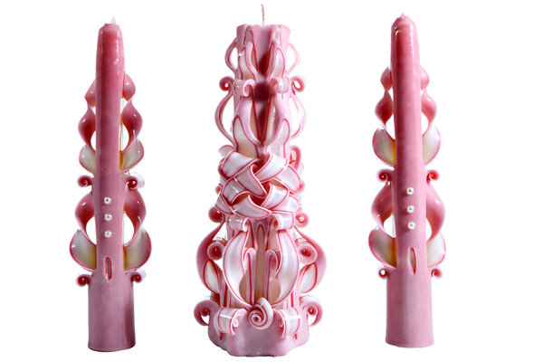 Three pink ribbon carved homemade Christmas candles isolated on 