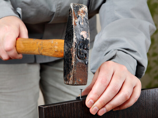 Монтаж мебели, рабочий процесс, молоток крупным планом ударяет в гвоздь
.