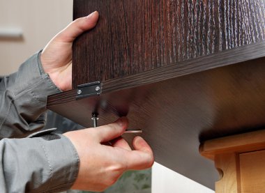 Allen furniture key in hand, fastens screw, close-up. clipart