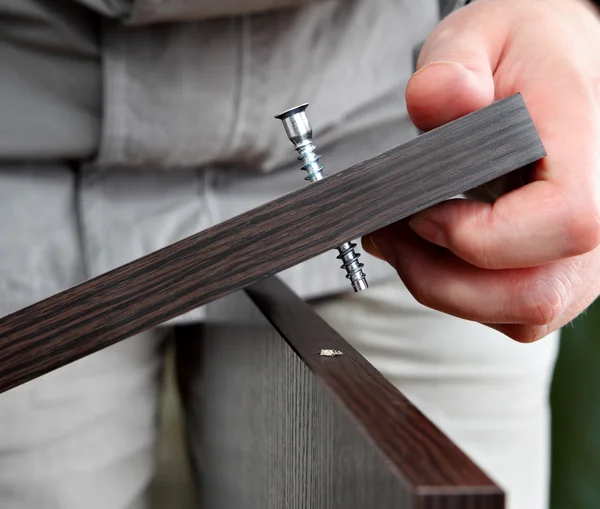 Screwing screw in chipboard furniture wenge. — Stock Photo, Image