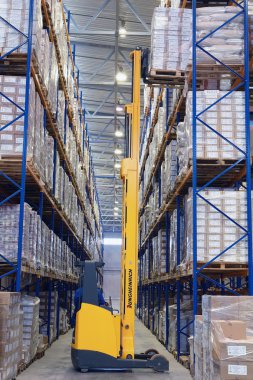 Sarı forklift raf üst rafta Paletleme yükseltir.