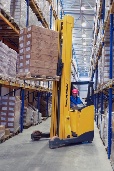 Gele voetgangers stacker liften pallet met vakken op de planken — Stockfoto