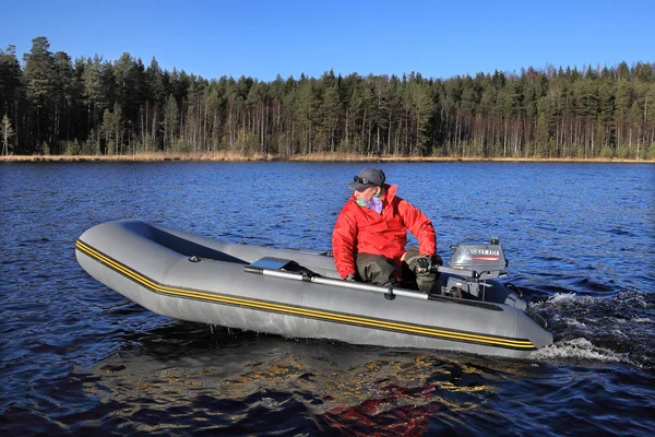 Pescador controla barco de goma inflable gris con un motor fueraborda . — Foto de Stock