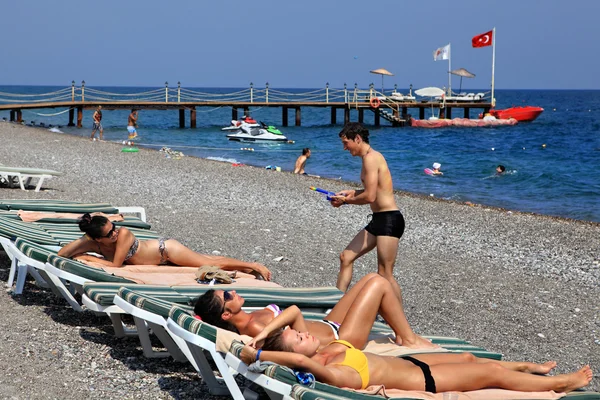 Ragazzi e ragazze prendere il sole sulla località balneare ciottolosa di Antalya . — Foto Stock