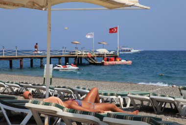 Şezlong ve şemsiyeler beach Resort, kız güneşlenmek tembel üzerinde.