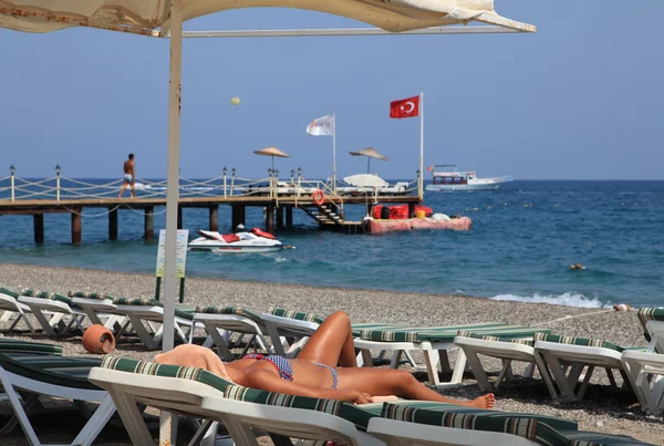 Sunbeds and umbrellas in beach resort, girl sunbath on lounger. — Stock Photo, Image