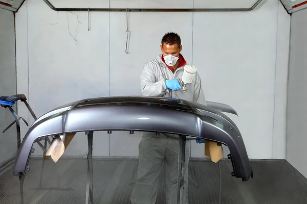 Painters use spray guns to apply paint to a bumper. — Stock Photo, Image