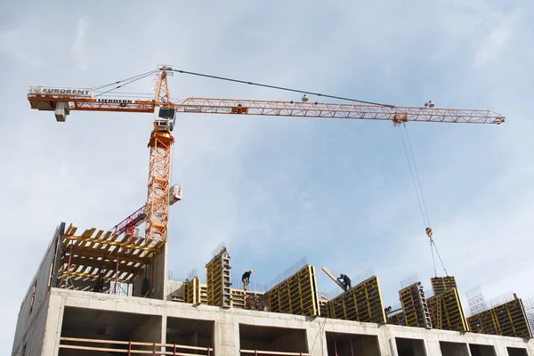 Construction of monolithic apartment house, tower crane lifts the load. — Stock Photo, Image