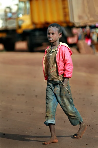 Dark skinned African boy walking barefoot in dirty jeans. — Stock Photo, Image