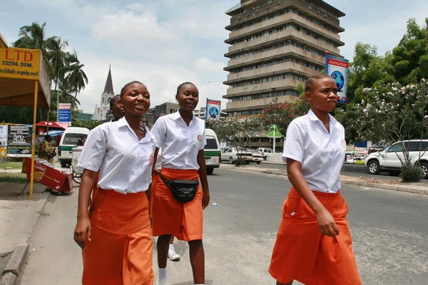 Čtyři černé africké ženy v uniformě, oranžové sukně a bílé tričko. — Stock fotografie
