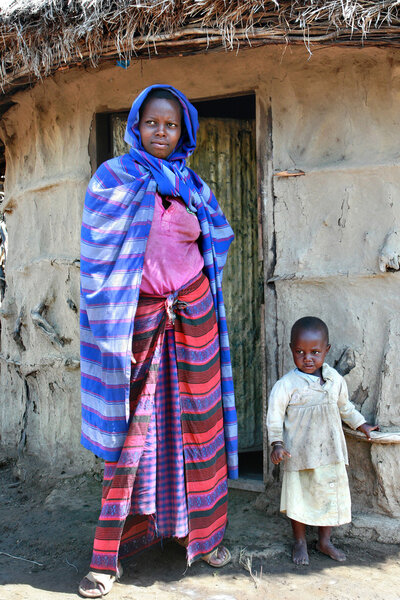 Maasai woman, with child standing at door of his hut.