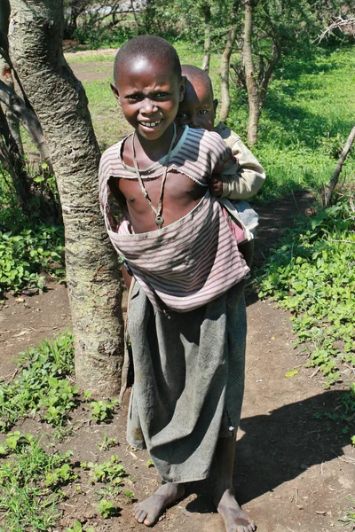 Masaï noir garçon porte sur le dos une petite soeur . — Photo
