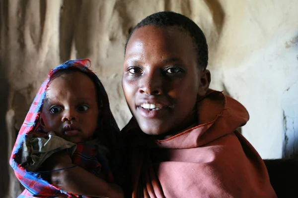 Portrait de femme noire avec bébé à l'intérieur des huttes tribu Maasai . — Photo