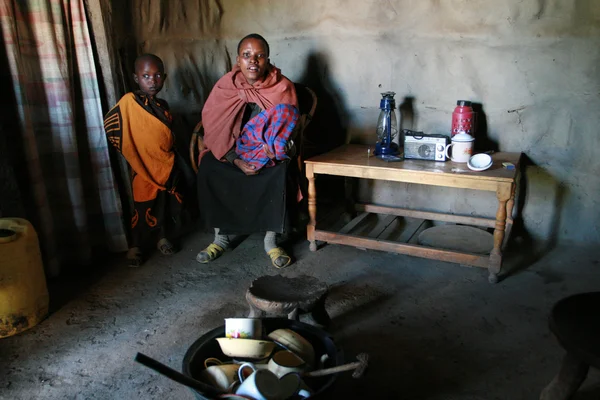 Inre syn på maasai hut, svart kvinna och barn inomhus. — Stockfoto