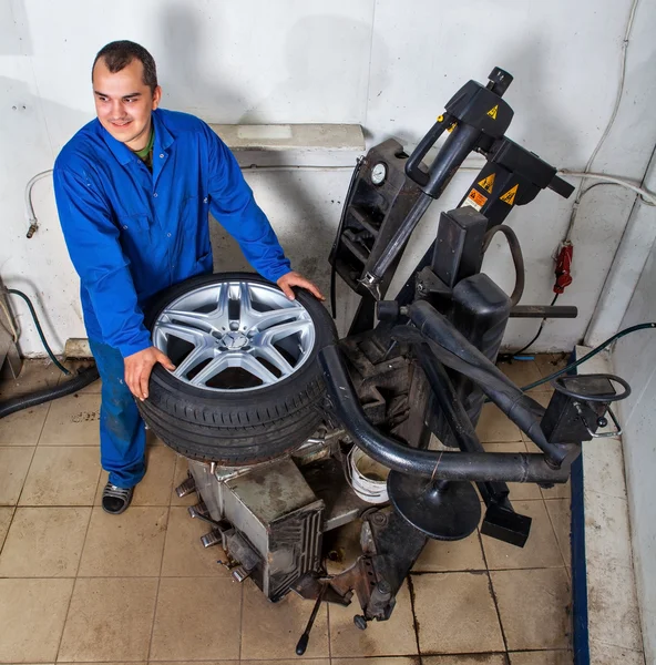 Auto repairman loading automobile car wheel at tyre fitting mach — Stock Photo, Image