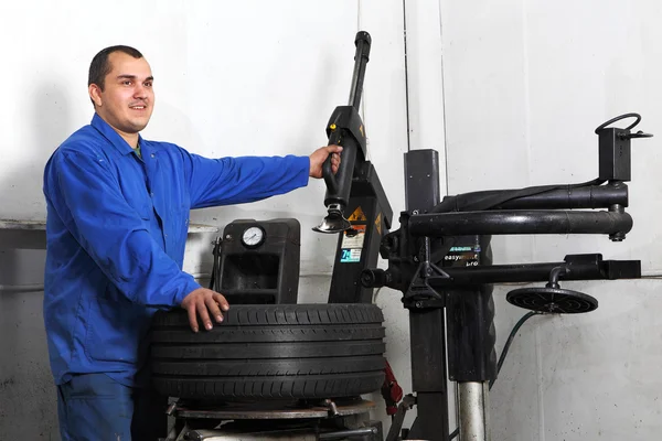 Auto repairman loading automobile car wheel at tyre fitting machine — Stock Photo, Image
