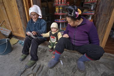 Two Asians and year-old child, on threshold of rural shop. clipart