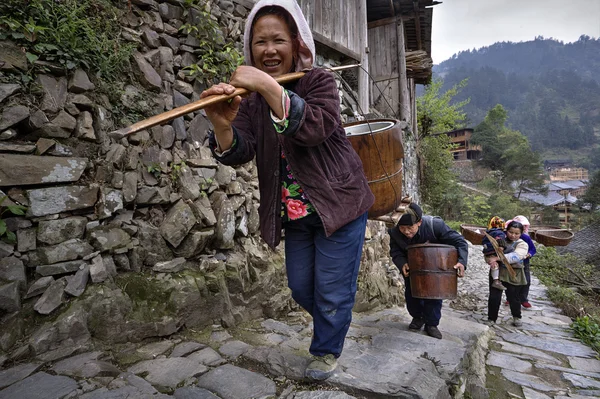 Los agricultores asiáticos suben por el sendero de montaña, con carga sobre los hombros . — Foto de Stock