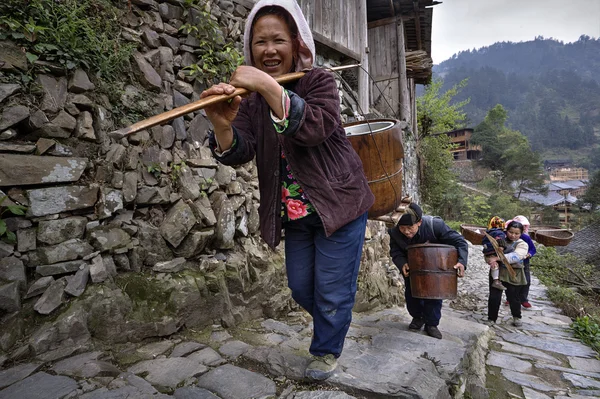 Asian farmers climb up mountain trail, with load on shoulders. — Stock Photo, Image