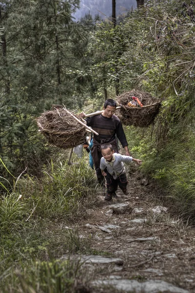 Padre e hijo agricultores que regresan del trabajo de campo, China rural . — Foto de Stock