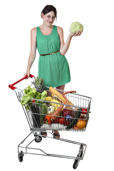 Einkaufswagen mit Lebensmitteln gefüllt, junge Frau hält Kohl in der Hand. — Stockfoto