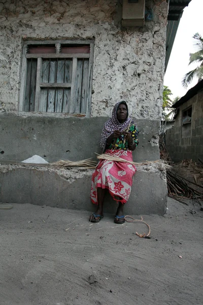 Rijpe zwarte Afrikaanse vrouw zit in de buurt van stenen huis, Zanzibar, Tanzania. — Stockfoto