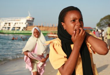 Müslüman siyah kız Zanzibar, Tanzanya'nın port yakınındaki plajda yürüyüş.