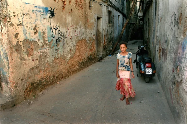 Arab girl with colorful dress, standing in courtyard dilapidated stone houses.
