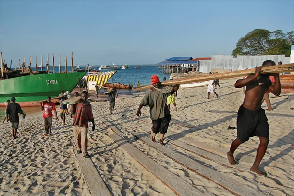 Afryki sztauerów rozładunku drewna statku w porcie Zanzibar, Tanzania. — Zdjęcie stockowe