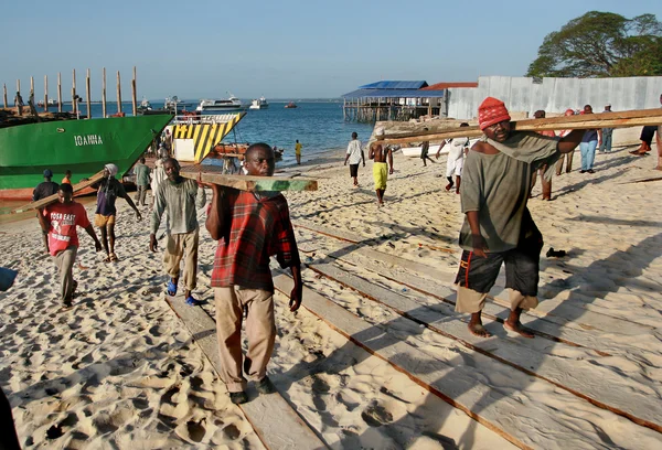 African longshoremen unload Lumber boat in port of Zanzibar. — Stock Photo, Image