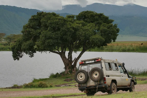 Velho jipe para turistas, estacionado perto do lago da floresta, cratera Ngorongoro, Tanzânia . — Fotografia de Stock