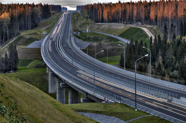 Sentieri luminosi Speedway nella foresta russa al tramonto . — Foto Stock